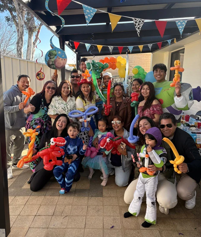Families and children in costume holding balloon creations at a birthday party
