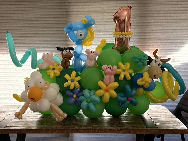 A farm-themed first birthday balloon display with animals and flowers